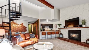 A modern living room with a fireplace, a kitchen area, and a staircase. - Breck-Ski IN Condo⛷Main Street 🏔 Views 😴 sleeps 8! $0 Cleaning fee (Breckenridge)