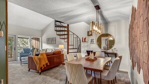A spacious living room with a large dining table, a cozy fireplace, and a spiral staircase leading to an upper level. - Breck-Ski IN Condo⛷Main Street 🏔 Views 😴 sleeps 8! $0 Cleaning fee (Breckenridge)