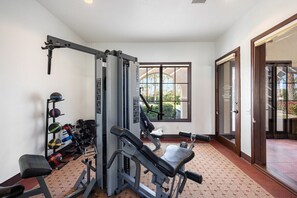 A gym with exercise equipment, a bench, and a window with a view of greenery. - Gated Oasis near Festivals | Pools & Spa Included (La Quinta)