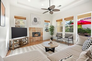 A modern living room with a fireplace, television, and comfortable seating. - Gated Oasis near Festivals | Pools & Spa Included (La Quinta)
