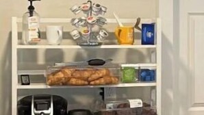 Een witte berging met planken waarop diverse keukenapparaten en spullen staan.