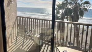 A balcony with a view of the ocean, a palm tree, and a chair. - Top Floor Ocean Front Remodeled Condo (San Diego)