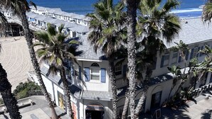 A beachfront building with a beach view, palm trees, and a bike parked outside. - Top Floor Ocean Front Remodeled Condo (San Diego)