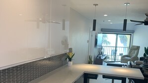 A modern kitchen with a large island, wooden cabinets, and a tiled backsplash. - Top Floor Ocean Front Remodeled Condo (San Diego)
