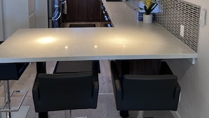 A modern kitchen with a central island, stainless steel appliances, pendant lighting, and a view to the outside. - Top Floor Ocean Front Remodeled Condo (San Diego)