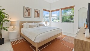 A bedroom with a large bed, two windows, a bedside table with a lamp, and a potted plant. - Experience luxury at Desert Retreat, a haven in La Quinta, near PGA West. (La Quinta)