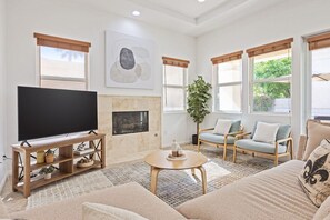 A living room with a flat-screen TV, a fireplace, a sofa set, and a potted plant.