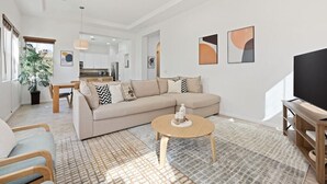 A modern living room with a sofa, coffee table, and TV stand. - Resort Living | Gym, Pool, Lounge & Spa Serenity (La Quinta)