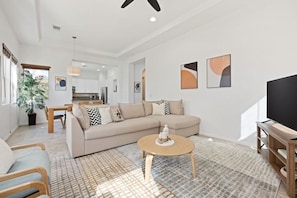 A modern living room with a sofa, coffee table, and TV stand. - Resort Living | Gym, Pool, Lounge & Spa Serenity (La Quinta)