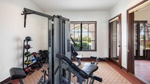 A gym with exercise equipment, a bench, and a window with a view of greenery. - Resort Living | Gym, Pool, Lounge & Spa Serenity (La Quinta)