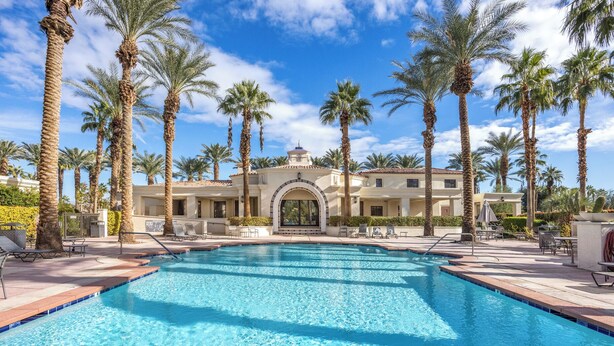 A swimming pool surrounded by palm trees and a building with a tiled roof. - Experience luxury at Desert Retreat, a haven in La Quinta, near PGA West. (La Quinta)