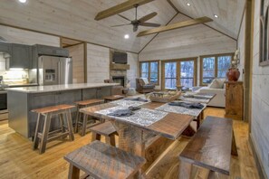A rustic kitchen with a central island, wooden benches, and a dining table with placemats. - Hot Tub- Modern Luxury -5 Bdrm-4 Kings- Pool Table (Blue Ridge)