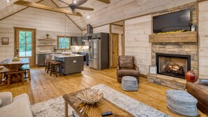 A spacious living area with a fireplace, wooden floors, a kitchen with modern appliances, and a ceiling fan. - Hot Tub- Modern Luxury -5 Bdrm-4 Kings- Pool Table (Blue Ridge)