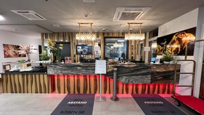 A hotel reception area with a modern design, featuring a marble reception desk, wooden paneling, and a chandelier. There are signs on the floor indicating social distancing measures. - Hotel Winterrot (Karlsruhe)