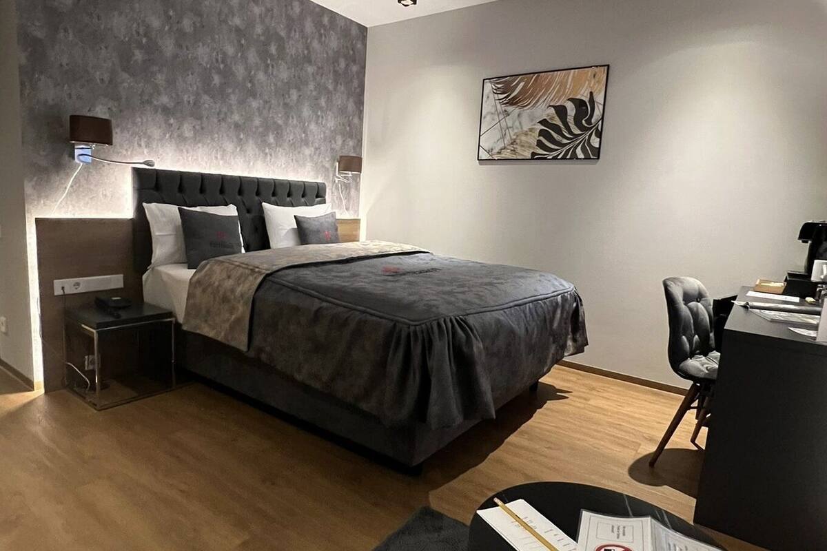 A modern bedroom with a large bed, a desk, and a chair.