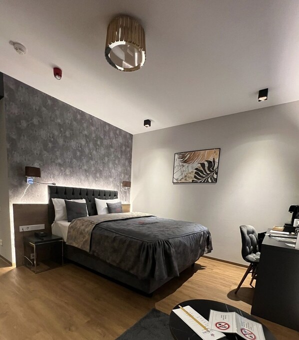 A modern bedroom with a large bed, a desk, and a chair. - Hotel Winterrot (Karlsruhe)
