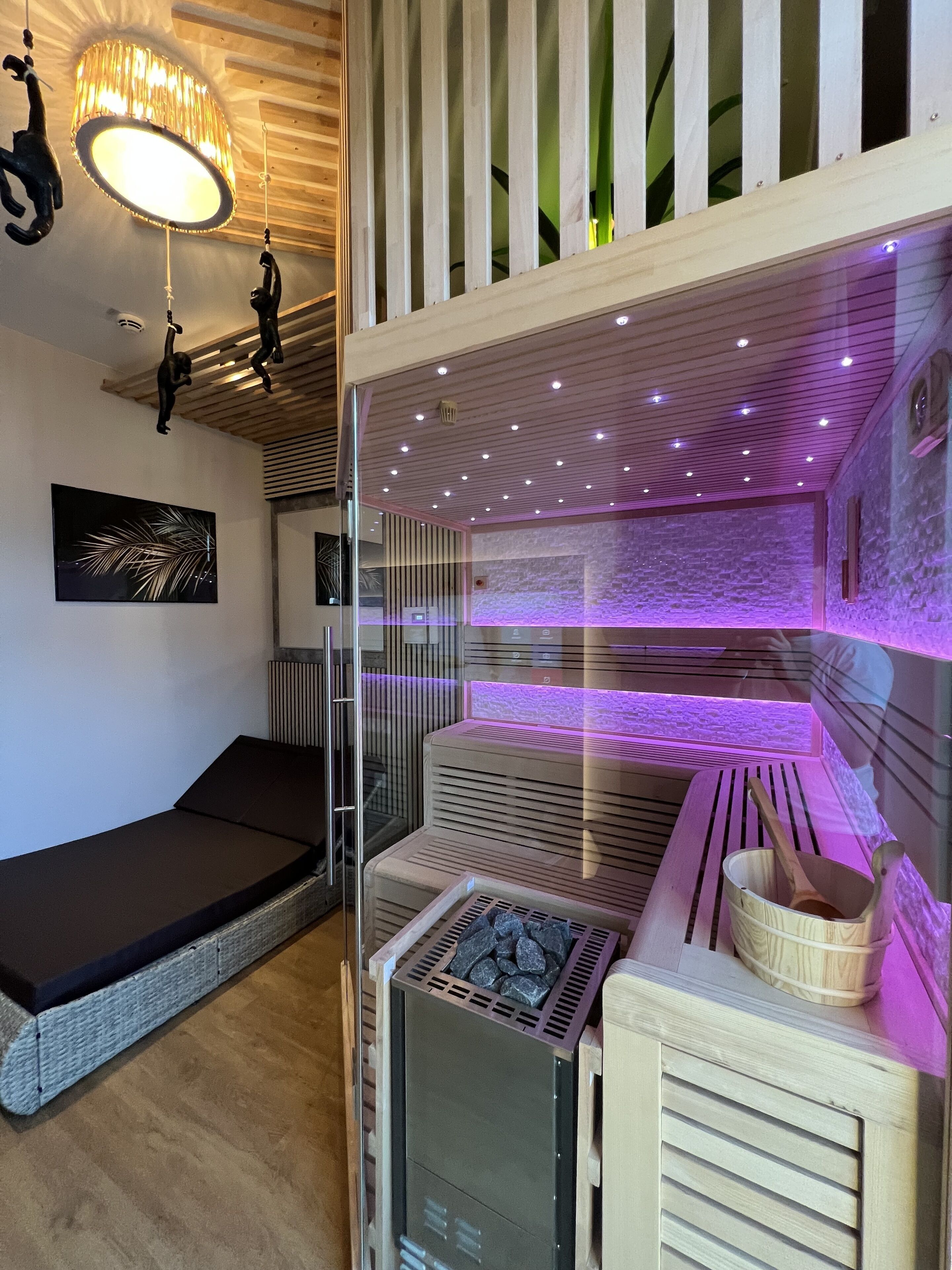 A spa room with a massage table, a stone wall, and a wooden cabinet with a wooden spoon.