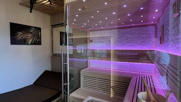 A spa room with a massage table, a stone wall, and a wooden cabinet with a wooden spoon.