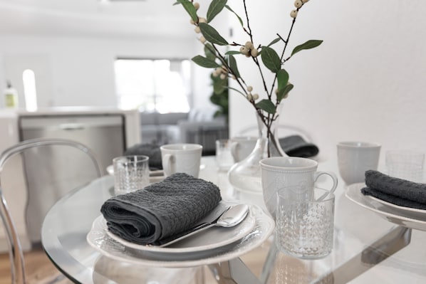 A modern dining area with a glass table, white plates, and a vase with a branch. - Relaxing, Luxury, All New - 10mins to Domain, 15mins to Downtown (Austin)