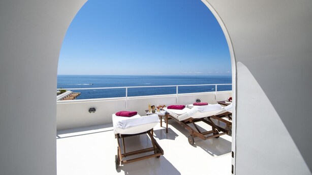 A sunlit balcony with a clear view of the sea, featuring two sun loungers and a table with amenities. - Villa Aurora in Praiano (Praiano)