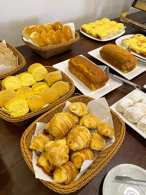 A variety of baked goods displayed on a table, including bread, rolls, and pastries. - Pousada Catedral (Petrópolis)