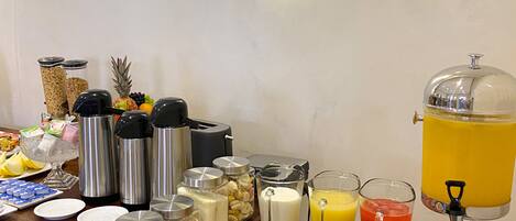 A breakfast buffet setup with various food items and beverages.