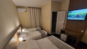 Une chambre d’hôtel avec deux lits, un téléviseur fixé au mur et un bureau avec une chaise.