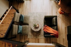 A top-down view of a room with a piano, two sofas, a coffee table with a plant, and a patterned rug.