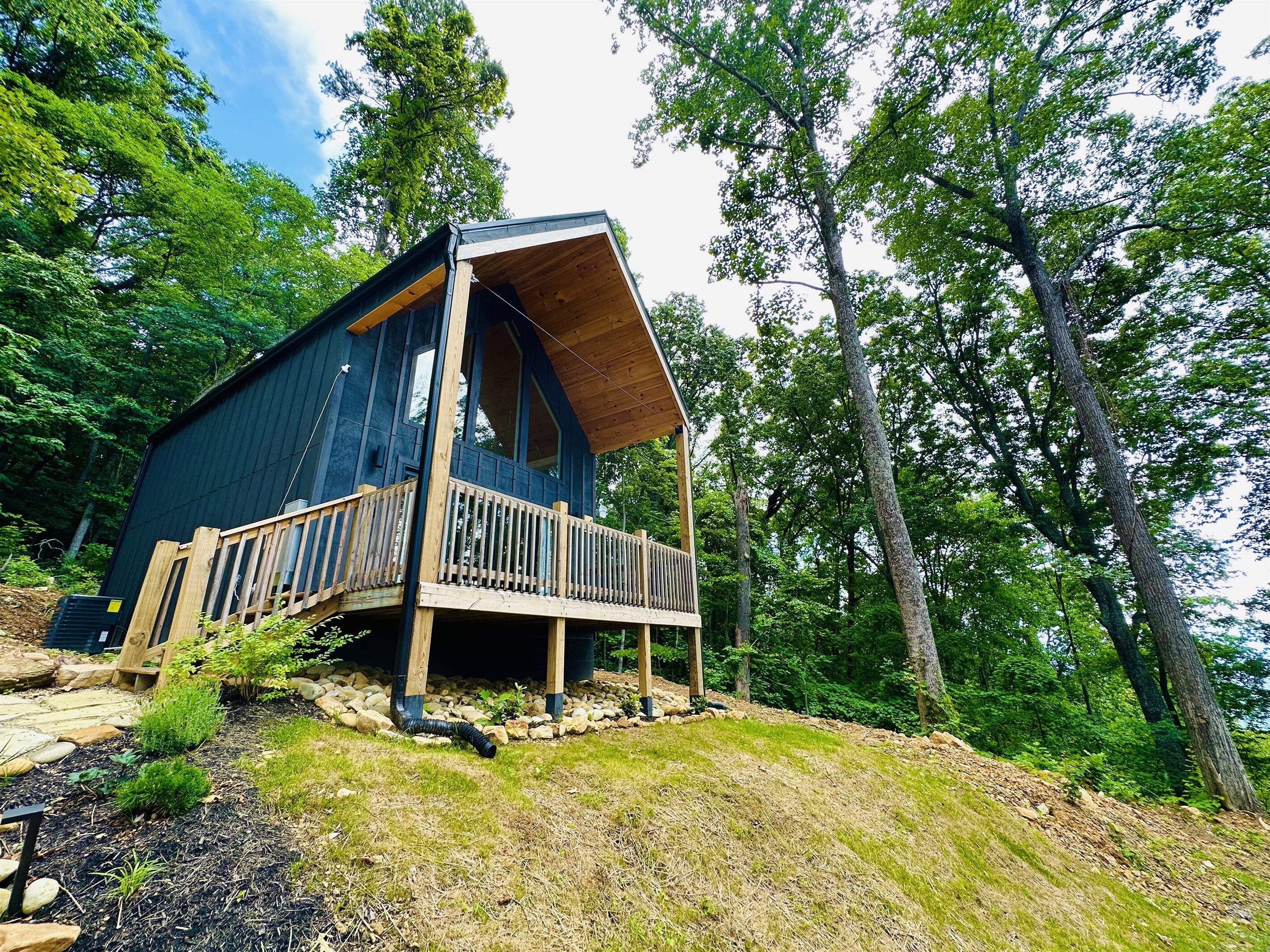 A cabin with a wooden deck and a large window, surrounded by trees.
