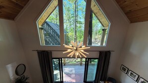 A dining area with a table set for four, a chandelier, and a view of the outdoors through large windows. - Early Fall Getaway - 2 (Sevierville)