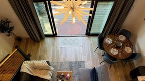 A modern living room with a dining area, a large window, and a ceiling light fixture. - Early Fall Getaway - 2 (Sevierville)