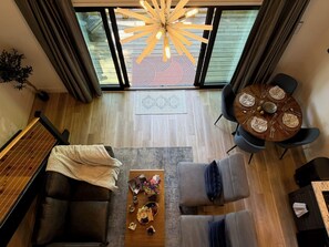 A modern living room with a dining area, a large window, and a ceiling light fixture. - Summer Adventure Awaits | Modern Cottage - 2 (Sevierville)