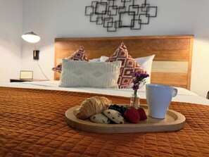 A neatly made bed with a wooden headboard, a bedside lamp, and a wall art piece.