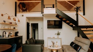 Ein moderner Loft-Wohnraum mit Küche, Essbereich und einer Treppe, die in einen oberen Bereich führt.
