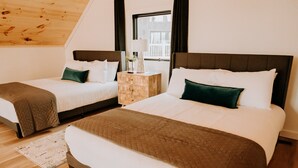 Ein Schlafzimmer mit zwei Betten, einem Nachttisch aus Holz, einer Lampe und Blick auf einen Balkon.