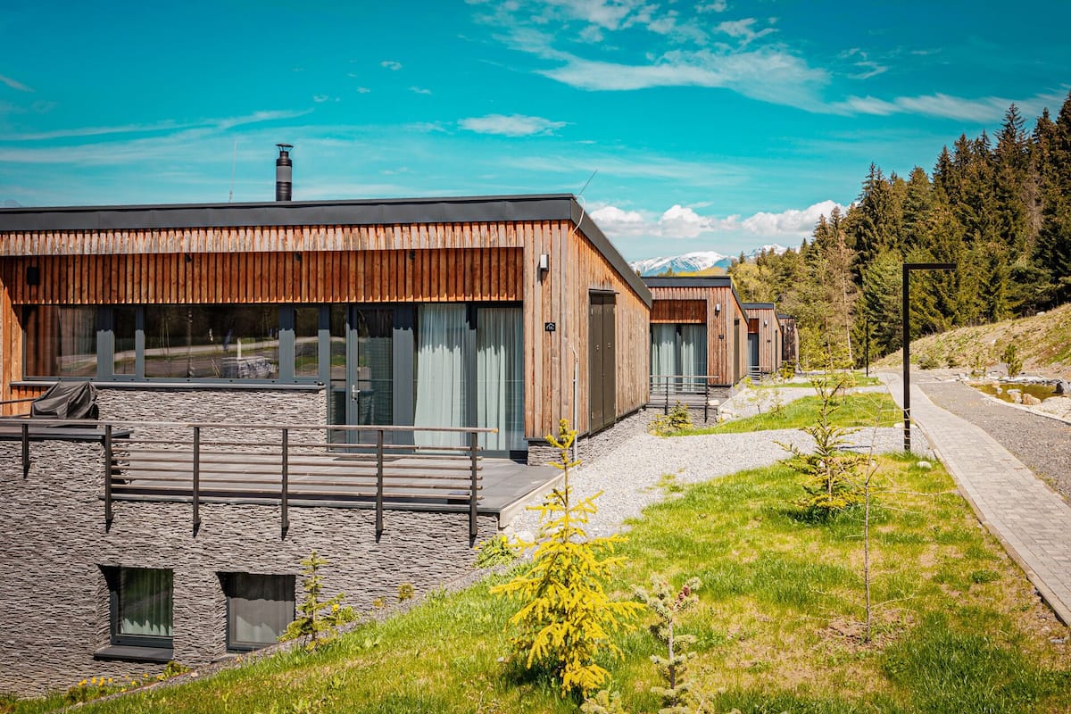 A modern building with a wooden facade, stone walls, and a clear view of the surrounding landscape.