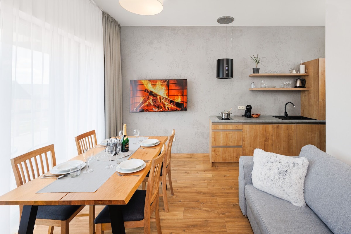 A modern kitchen with wooden cabinets, a built-in oven, and a hanging pot rack.