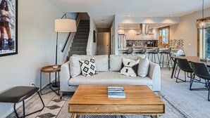 Una sala de estar moderna con un sofá, una mesa de centro y una escalera que lleva a una cocina.