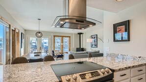 Una cocina moderna con campana extractora de acero inoxidable, encimeras de granito y horno empotrado.