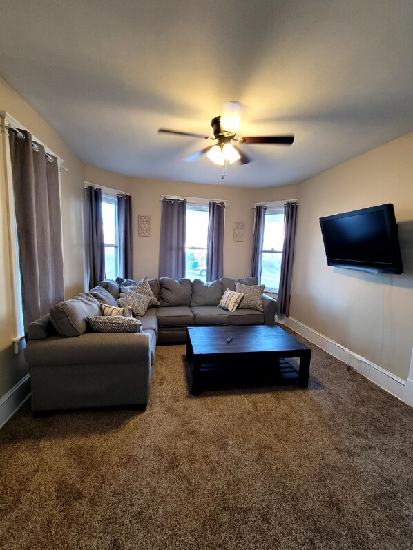 A living room with a sectional sofa, a coffee table, and a ceiling fan.