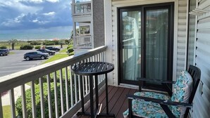 Ein Balkon mit Tisch und Stuhl, Blick auf den Ozean und Autos im Hintergrund.