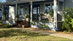 A single-story house with a covered porch, a brick base, and a number '308' on the front. - Charming Bungalow On Main St & the Swamp Rabbit Trail with Private Pool (Travelers Rest)