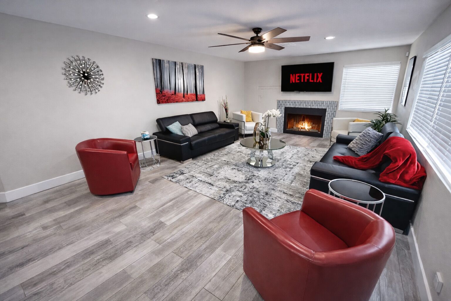 A modern living room with a fireplace, a ceiling fan, and a TV mounted on the wall.