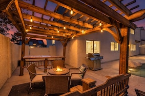 An outdoor patio with a pergola, a fire pit, a grill, and a pool.