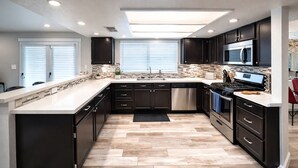 A modern kitchen with dark cabinetry, a stainless steel range, and a large island.