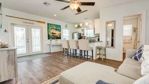 A spacious living area with a dining table, chairs, a sofa, and a ceiling fan.