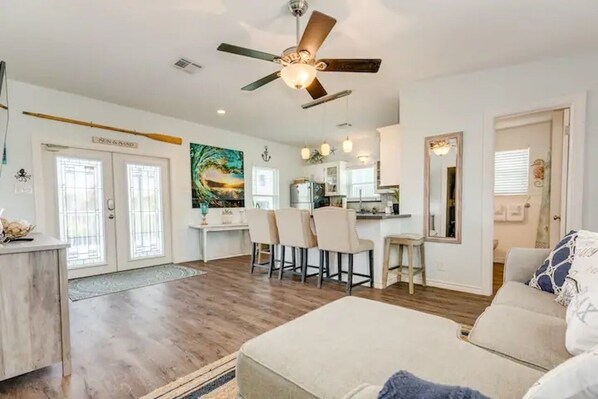A spacious living area with a dining table, chairs, a sofa, and a ceiling fan.