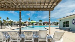 A pool area with lounge chairs and a covered seating area.