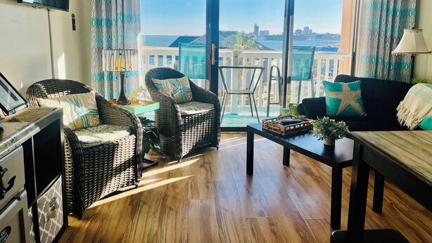 Ein Wohnzimmer mit Rattanmöbeln, einem Flachbildfernseher und Blick auf den Strand.