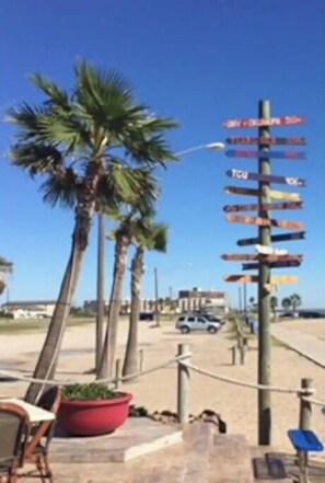 A palm tree-lined pathway with a signpost indicating directions to various destinations. - Beautiful Bayfront Water View (Corpus Christi)